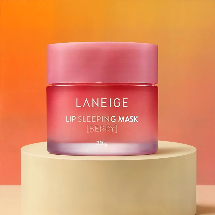 Product photograph by Laneige of a Lip Sleeping Mask Berry jar positioned on a cream cylindrical pedestal featuring a frosted pink gradient glass container, a matte pink lid, and a vibrant orange-to-peach background