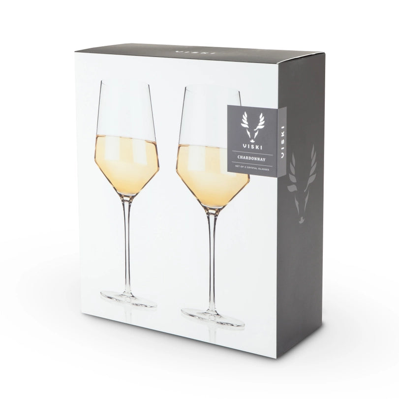 Product photography by Viski of a set of two crystal Chardonnay wine glasses on a grey and white retail box featuring elegant long stems, golden liquid, and a signature stag logo