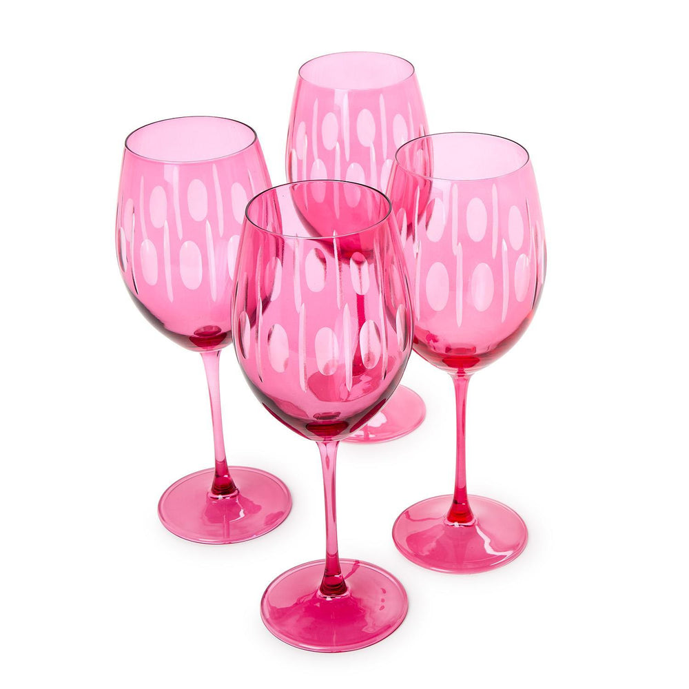 Glassware set of four vibrant fuchsia wine glasses on a white background featuring etched white oval patterns, vertical stripe details, and long slender stems