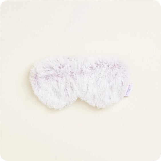 Studio photograph of a Wild Friends plush sleep mask on a cream background featuring shaggy lavender-colored faux fur and a visible white brand label on the right side
