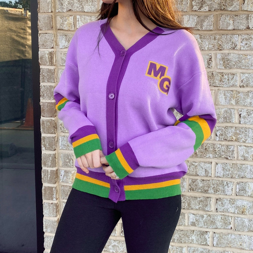 Lavender cardigan with purple trim, an MG letter patch and purple, green and gold striped cuffs and hem
