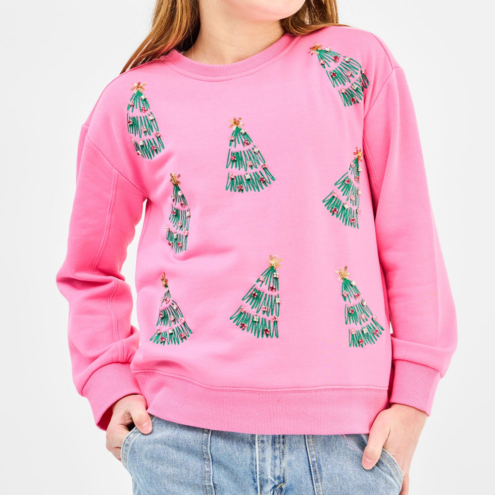 Photograph of a pink crew-neck sweatshirt worn by a child featuring green embroidered Christmas trees with colorful beaded ornaments and shimmering gold stars