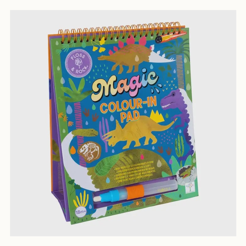 Spiral-bound activity book by Floss & Rock featuring a dinosaur-themed Magic Colour-In Pad set against a volcanic landscape with a vibrant purple Tyrannosaurus Rex, a yellow Triceratops, and a refillable water pen stored in the base