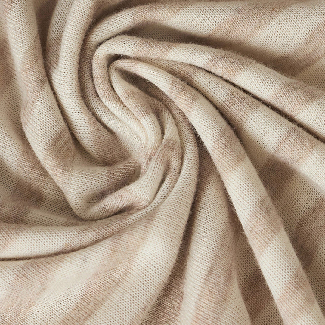 Close-up photograph of a finely knitted beige and cream striped textile arranged in a central spiral fold that creates soft shadows and showcases the intricate yarn texture