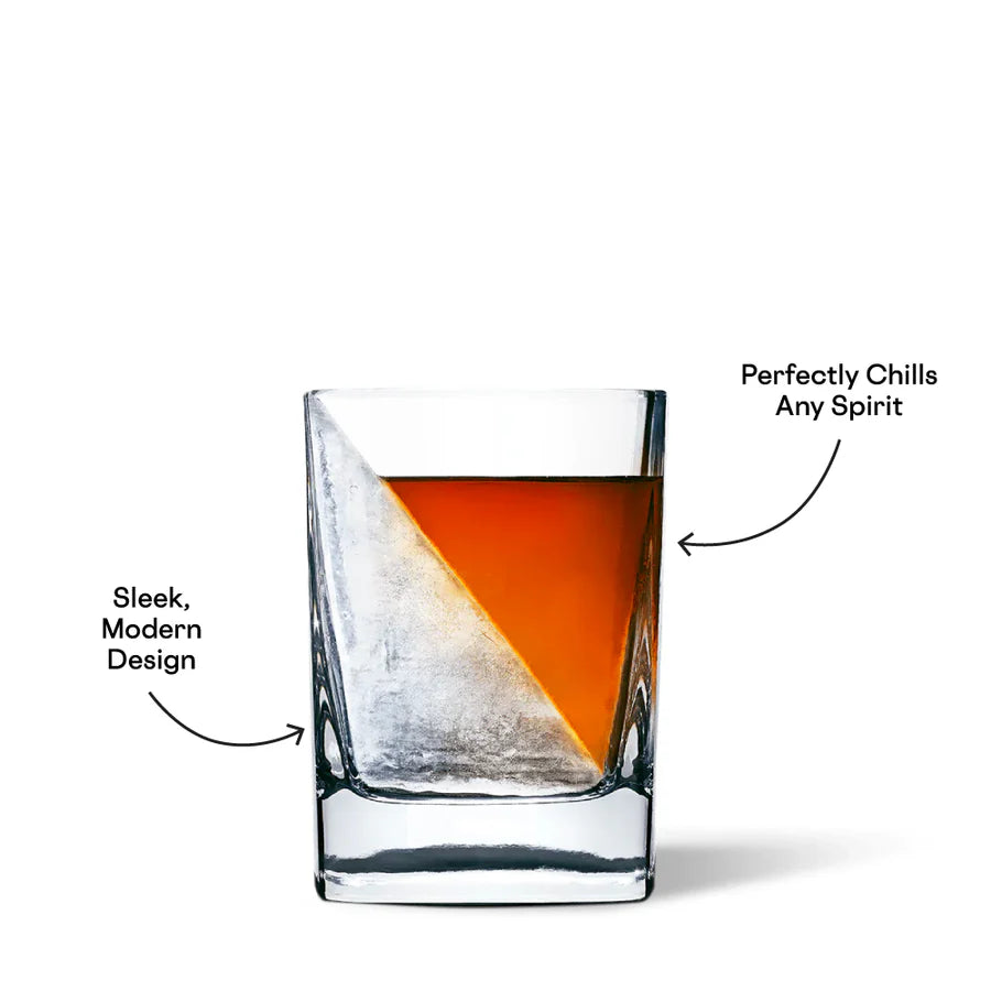 Commercial product photograph of a whiskey glass on a white studio background featuring a golden-amber spirit chilled by a large diagonal ice wedge with black promotional text and curved arrows