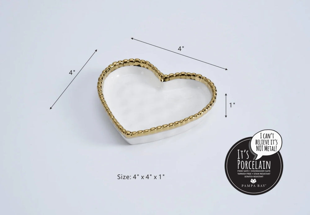 Pampa Bay porcelain heart-shaped dish shown on a white background featuring the Pampa Bay brand seal, a metallic gold beaded rim, and black dimensional measurement arrows indicating its four by four by one inch size