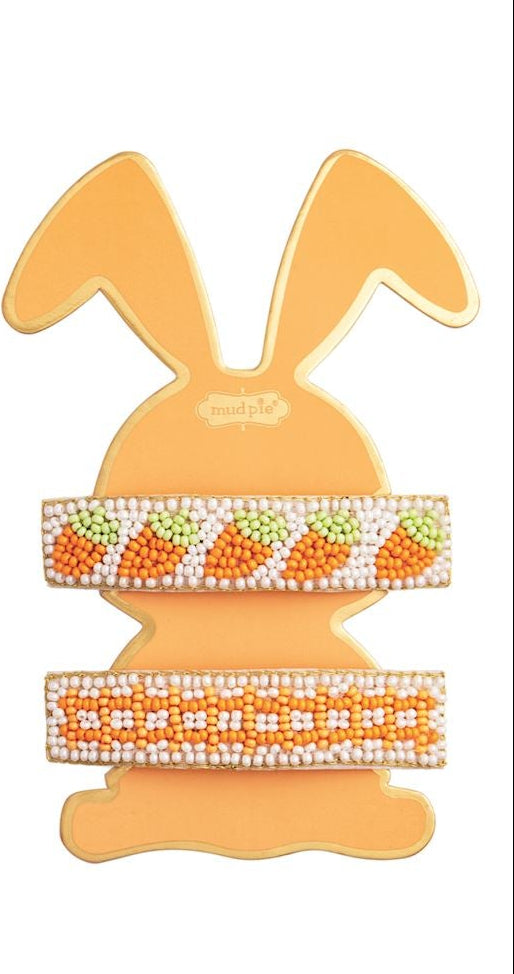 Hand-beaded hair barrettes by Mud Pie featuring vibrant orange carrot patterns and white geometric seed beads displayed on a yellow rabbit silhouette card