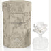 Commercial product photography of a Grand Casablanca Fleur d’Oranger room diffuser set featuring a beige hexagonal damask-patterned box and a clear glass bottle with a white multi-layered ceramic flower topper against a minimalist studio background