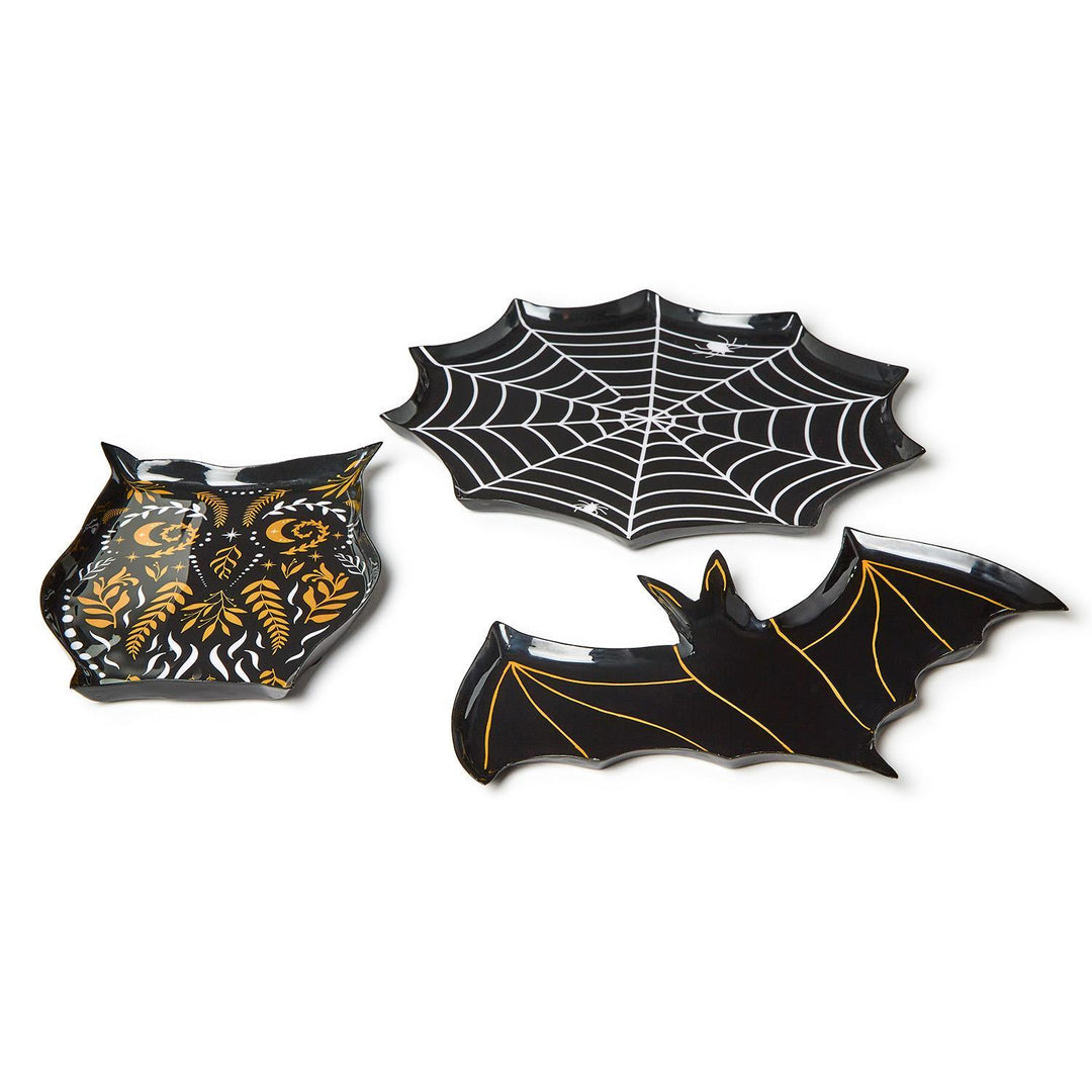 Angled view of three black Halloween plates shaped like an owl, a spiderweb and a bat