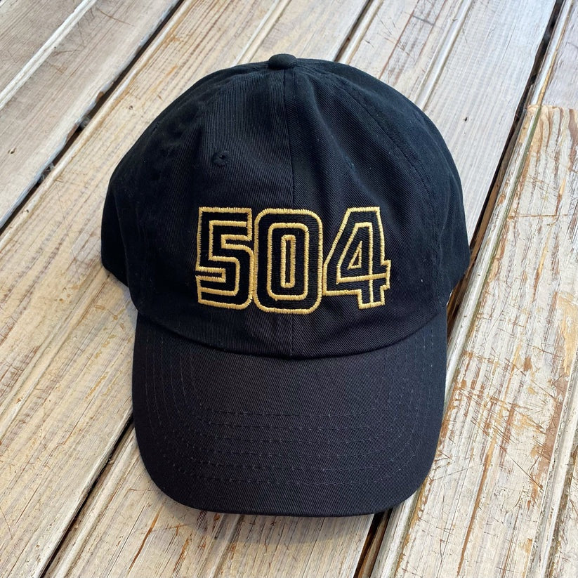 Embroidered cotton twill baseball cap featuring the New Orleans 504 area code in raised gold block numbers resting on weathered wooden planks