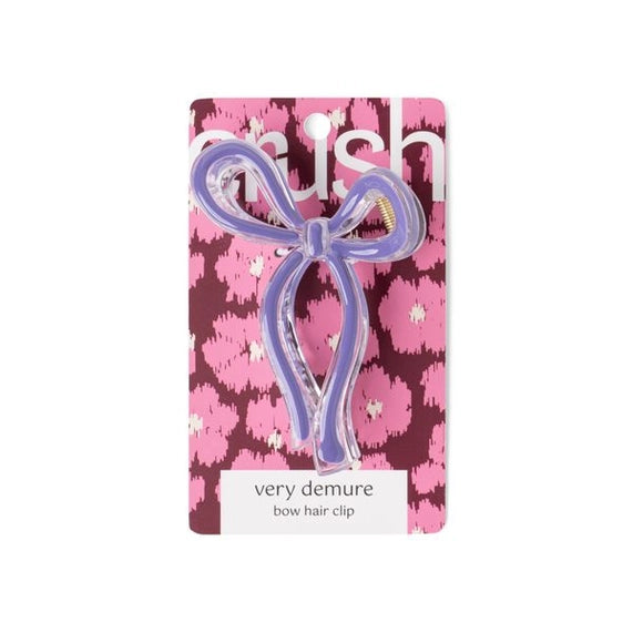 Product photograph by Crush of a lavender bow hair clip on a pink floral leopard print backing card featuring the very demure label and translucent purple plastic ribbon details