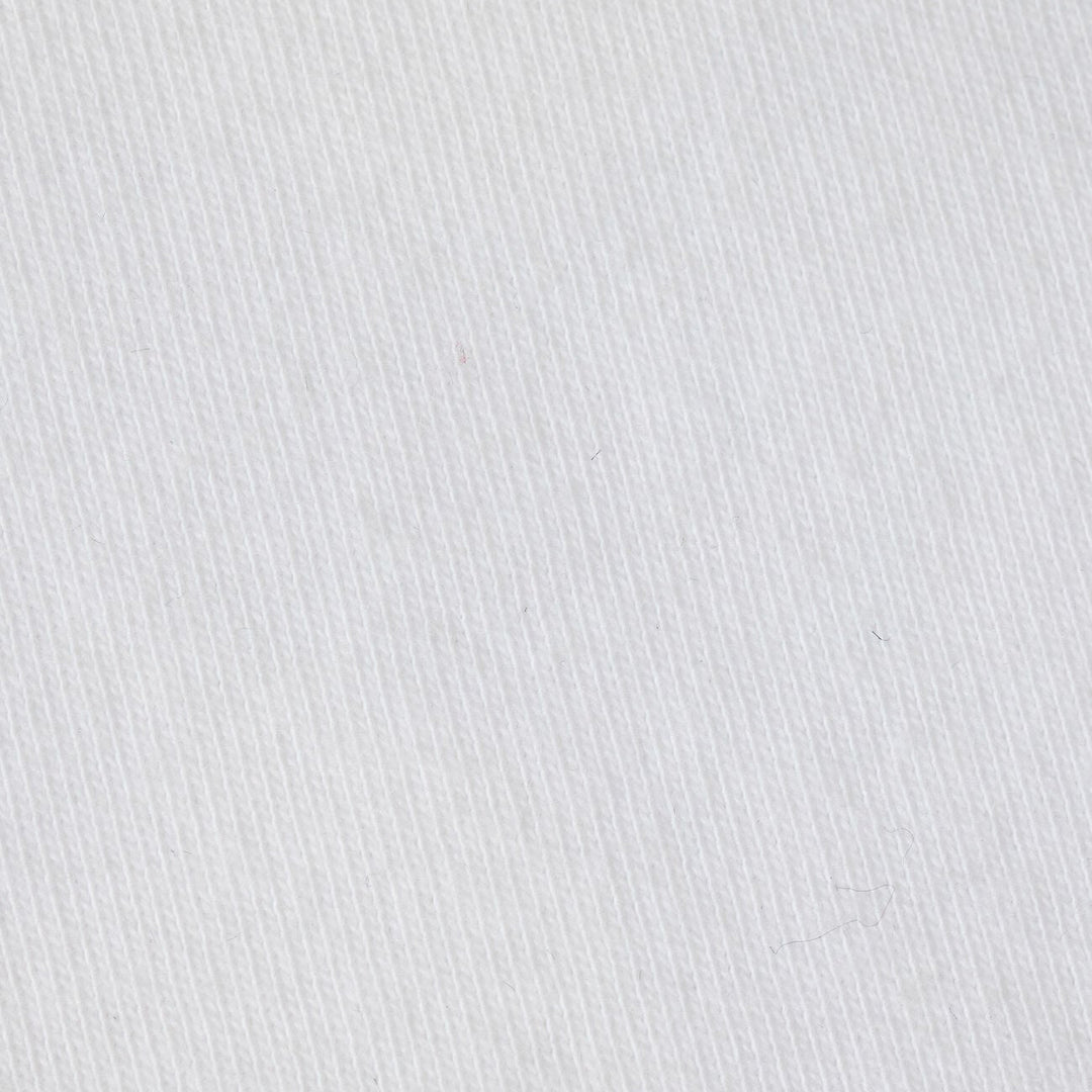 Photograph of white cotton twill fabric featuring a prominent diagonal weave pattern and tiny stray dark fibers on its textured surface