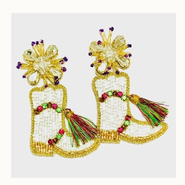Hand-beaded cowboy boot earrings featuring white woven panels with gold seed bead borders, vibrant multi-colored tassels, and sparkling crystal flower studs with purple accents set against a white background