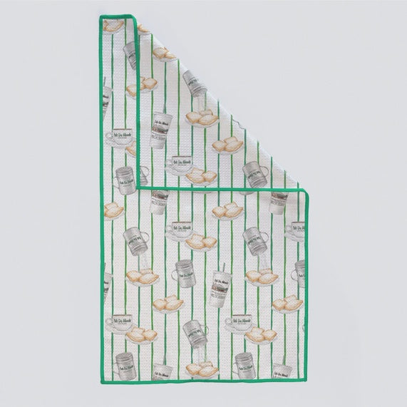 Kitchen towel with beignets and coffee cups on green pinstripes, corner folded back
