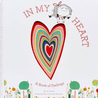 Illustrated book cover by Christine Roussey for the book In My Heart featuring a large central die-cut heart with concentric rainbow layers, a whimsical girl with a red hair bow, and stylized green houses along the bottom margin