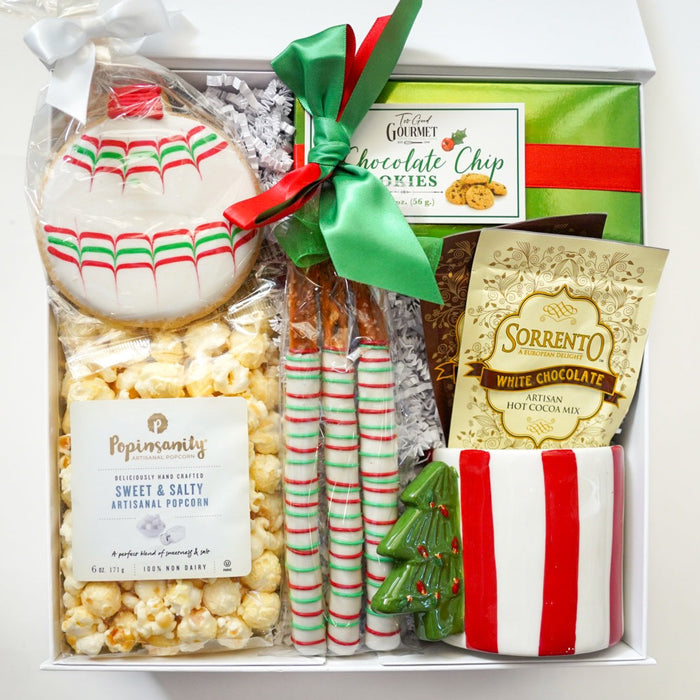 Gift box with Christmas-themed snacks and treats on a white background