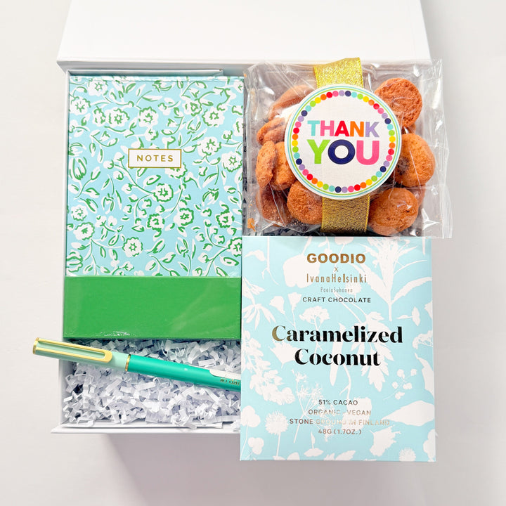 Packaged caramelized coconut with a green notebook and pen on a white background