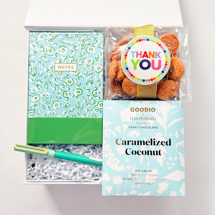 Packaged caramelized coconut with a green notebook and pen on a white background