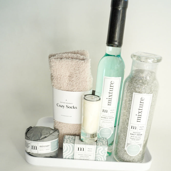 Bathroom products including a bottle, candle, and towel on a white surface