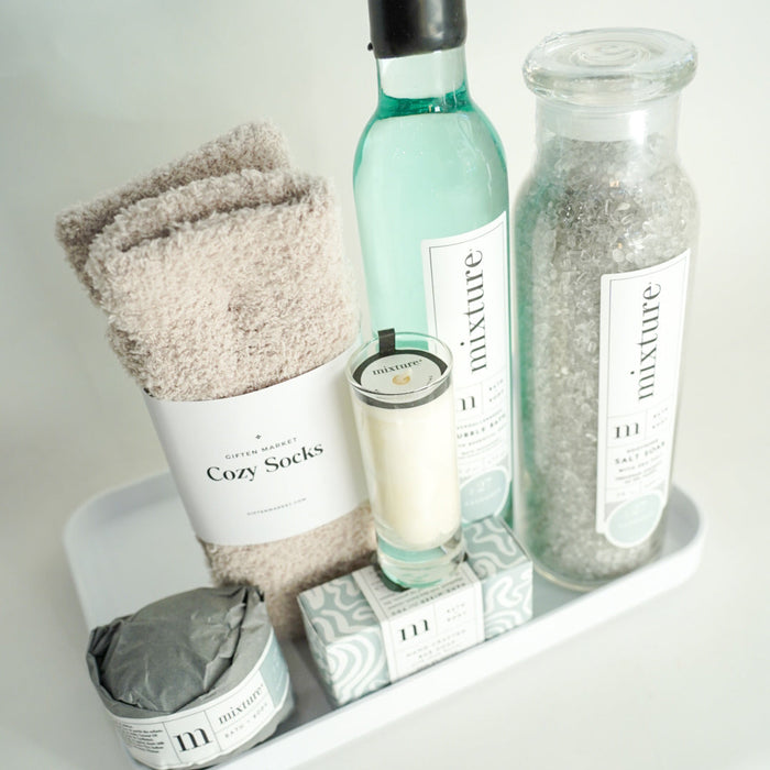 Bath products including socks, bottles, and a candle on a white surface