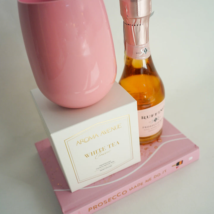 Pink cup and bottle of Prosecco on a pink book with a white label.