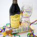 Bottle of Caymus Cabernet Sauvignon with a glass, Mardi Gras beads, and a wrapped gift on a white background
