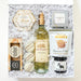 Gift basket with wine, snacks, and other items on a white background