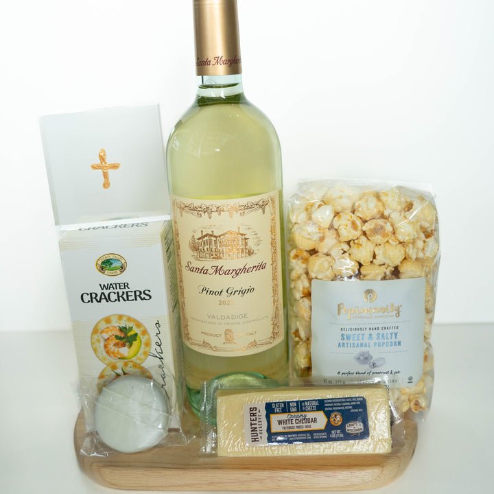 Photograph of a gourmet wine and snack gift set on a wooden board featuring a bottle of 2023 Santa Margherita Pinot Grigio, Hunter&