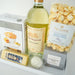 Tray with a bottle of wine, popcorn, cheese, and other snacks on a light background