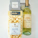 Packaged popcorn and a bottle of white wine on a white background
