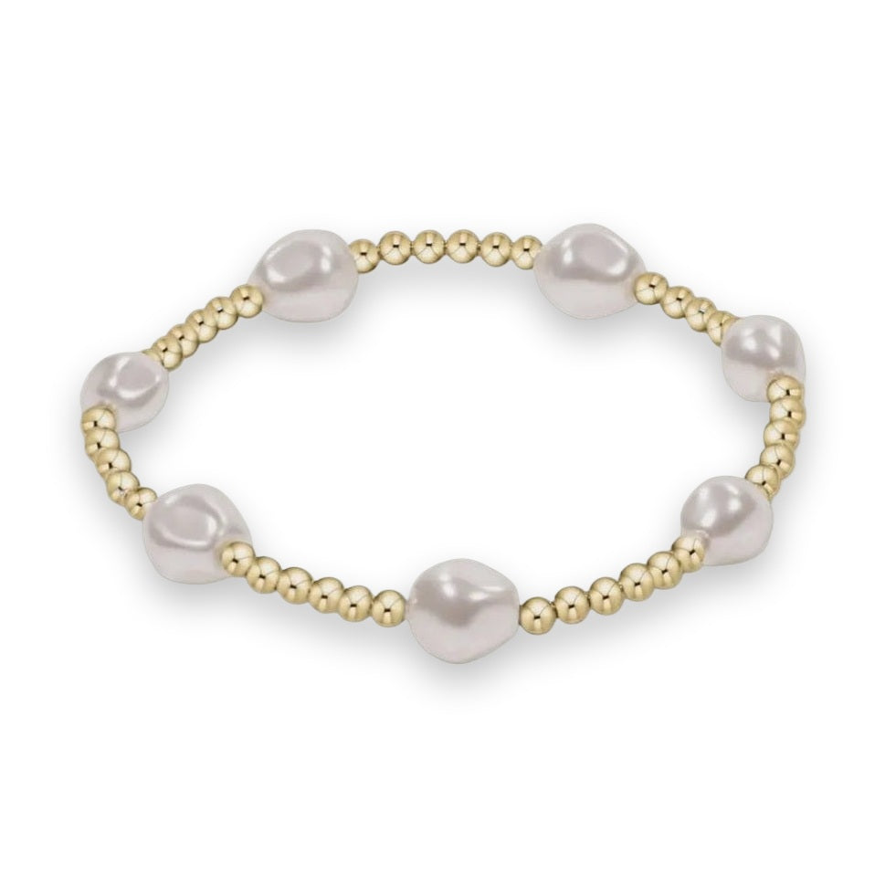 Studio photograph of a beaded bracelet featuring six lustrous white baroque pearls alternating with clusters of six small polished gold beads on a clean neutral background