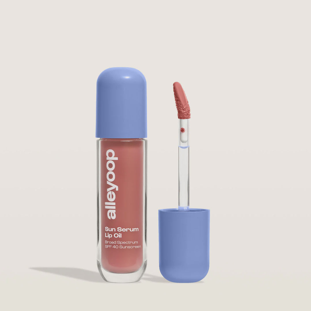 Product photograph by Alleyoop of the Sun Serum Lip Oil with SPF 40 featuring a periwinkle blue domed cap, the brand logo on a clear tube of dusty rose serum, and an upright applicator wand on a neutral background