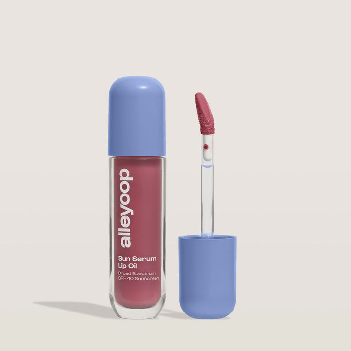 Alleyoop Sun Serum Lip Oil in a cool mauve shade with periwinkle cap and applicator beside it