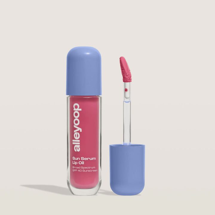 Alleyoop Sun Serum Lip Oil in a vibrant pink shade with periwinkle cap and applicator beside it