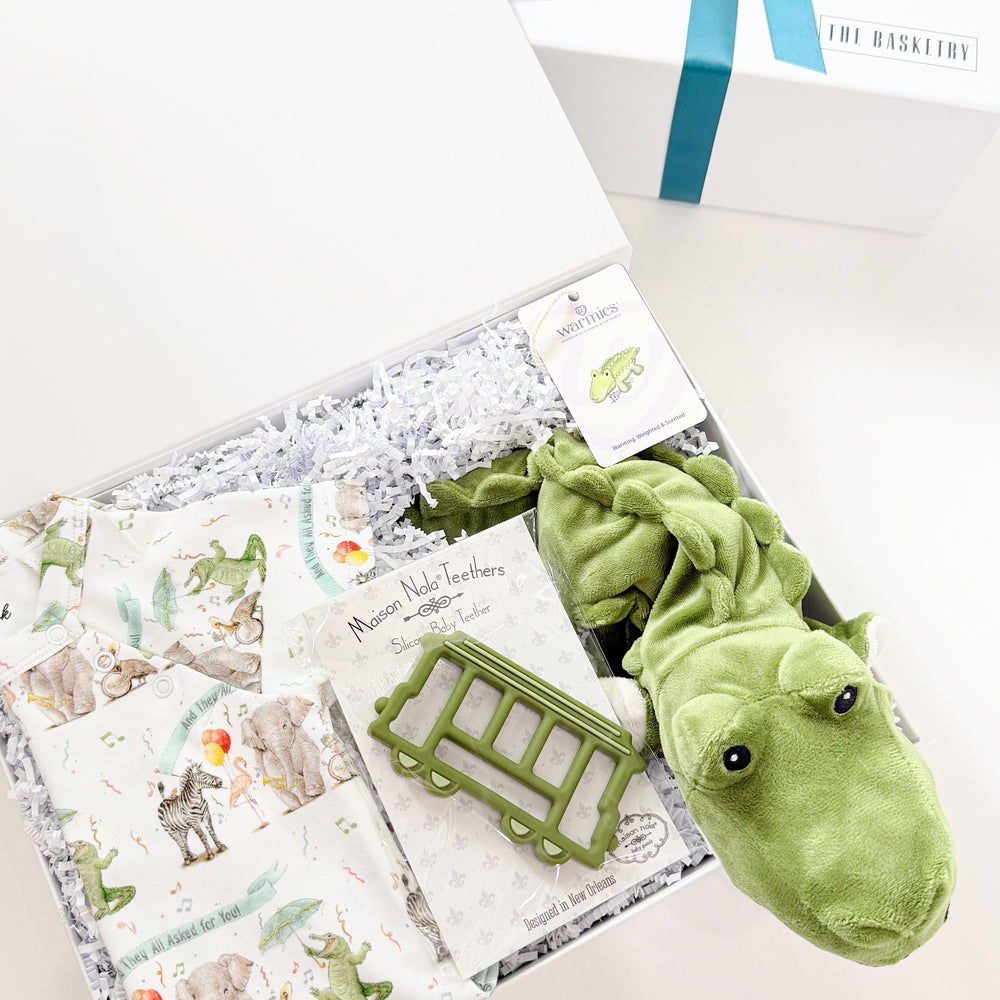 Green alligator toy with a book and gift box on a white surface