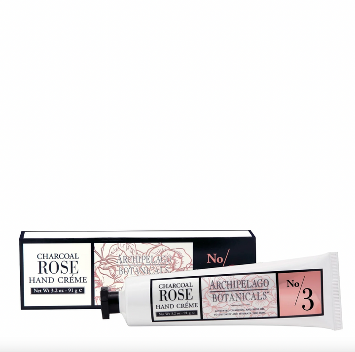 Commercial product photography by Archipelago Botanicals of Charcoal Rose Hand Crème displayed on a white background featuring a white squeeze tube with a black octagonal cap and a box decorated with pink floral line art and the No 3 label