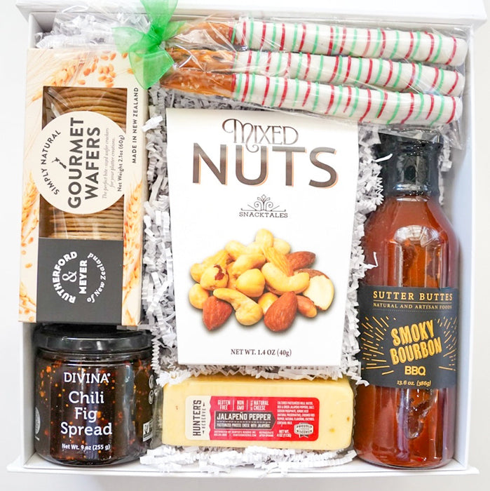 Gift box with gourmet wafers, mixed nuts, chili fig spread, and barbecue sauce on a white background