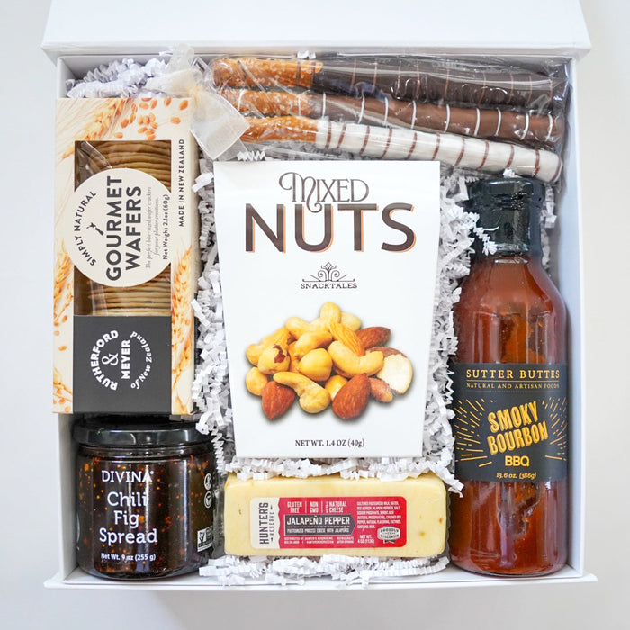 Gift basket with gourmet items including a bottle of butter, nuts, and spreads.