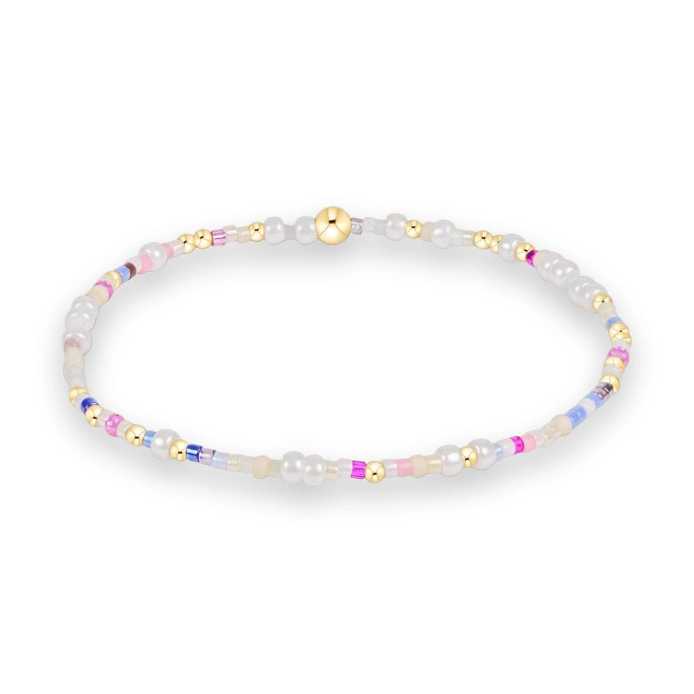 Handcrafted beaded jewelry featuring a colorful seed bead bracelet on a white background with pastel pink and blue accents, interspersed with small gold spheres and iridescent white beads
