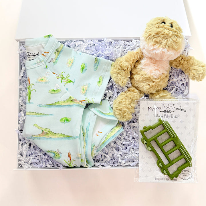 Baby gift set with teddy bear, blanket, and book on a textured surface