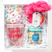 Gift box with birthday-themed items including a tumbler, cookies, and a pink flower on a white background.