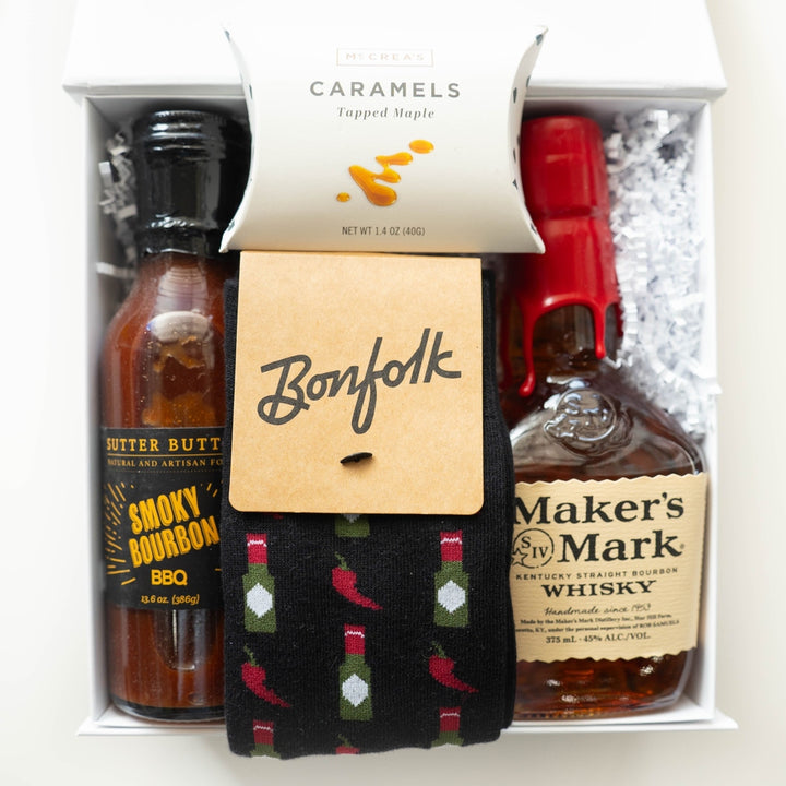 Photograph of a curated gourmet gift box featuring a bottle of Maker&