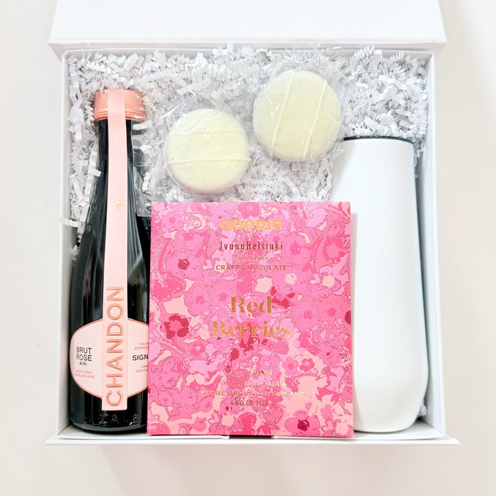 Gift set with champagne bottle, chocolates, and pink box on a white background