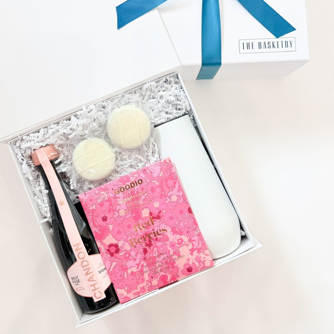 Gift set with champagne bottle, chocolates, and pink box on a white background
