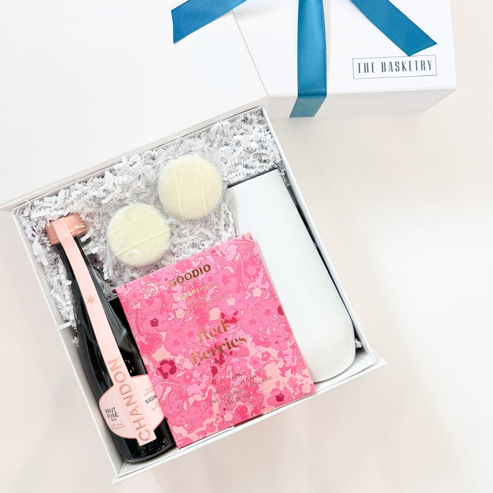 Gift set with champagne bottle, chocolates, and pink box on a white background