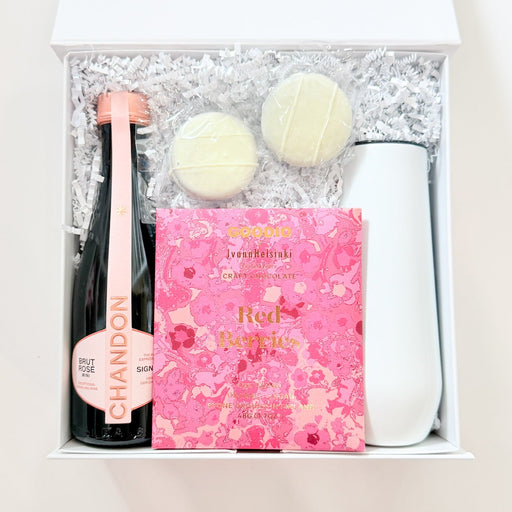 Gift set with champagne bottle, chocolates, and pink box on a white background