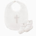 Product photograph of a white cotton Christening set featuring a baby bib and matching socks displayed on a plain background with an intricate shimmering beaded cross and small embroidered religious motifs on the folded cuffs