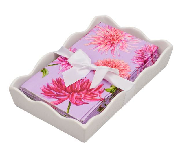 Product photograph of a decorative napkin set featuring paper guest towels with a vibrant pink dahlia floral pattern on a lavender background, nestled in a white scalloped-edge ceramic holder and tied with a decorative white satin ribbon bow