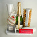 Gift set with champagne, cookies, and snacks on a white surface