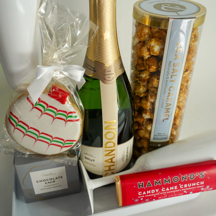 Bottle of Chandon champagne with a cookie, popcorn, and candy on a tray.